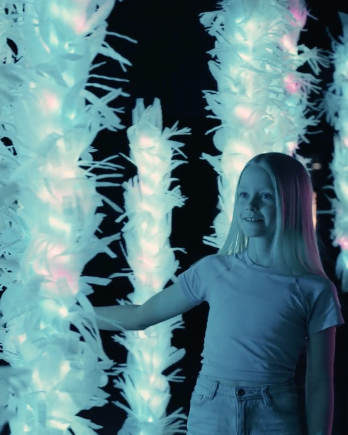 Une jeune visiteuse découvre une installation lumineuse interactive